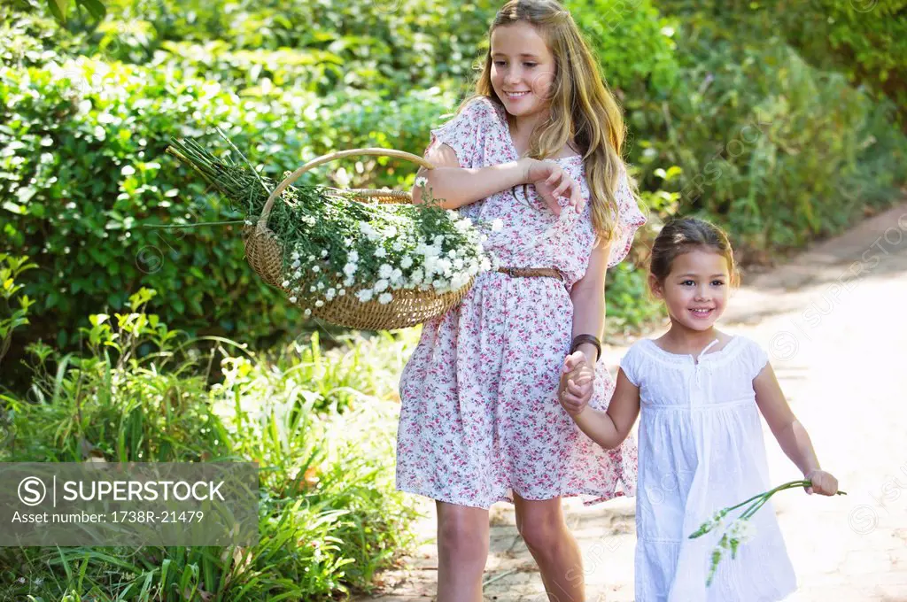 Happy siblings walking holding hands in garden