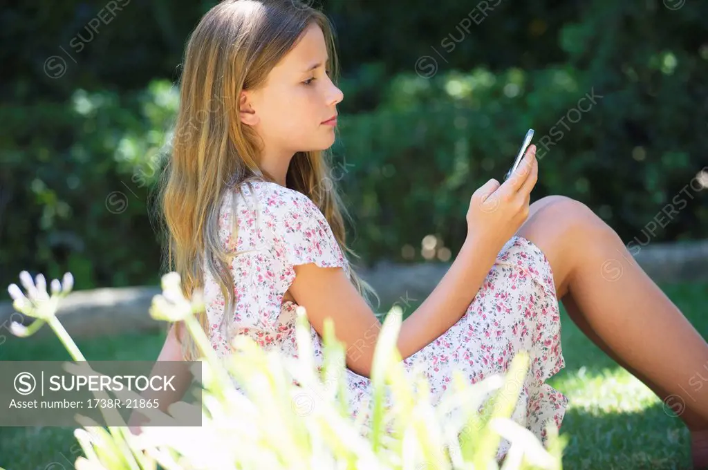 Cute little girl using a mobile phone outdoors