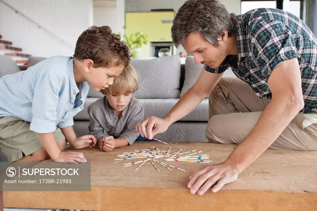 Man playing pick up sticks with his sons
