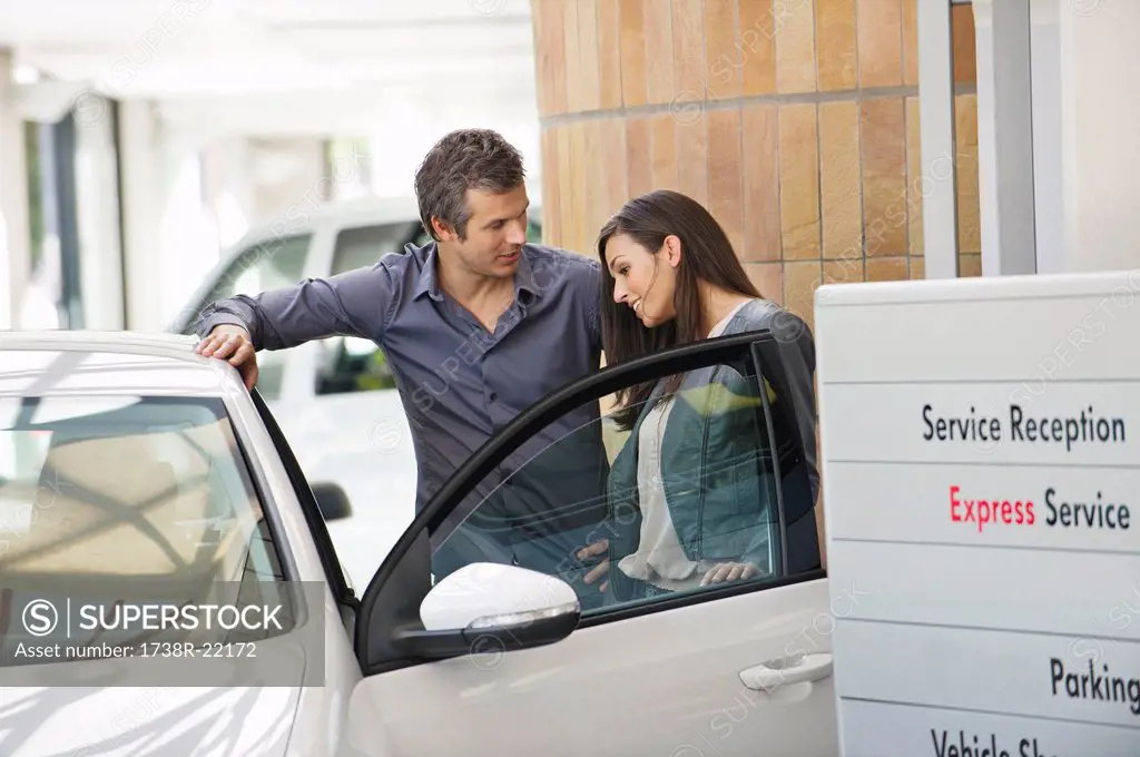 Couple looking inside car at showroom