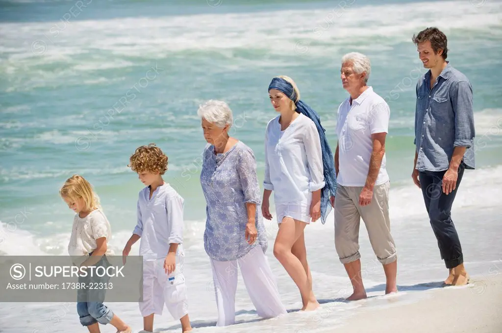 Multi generation family walking in a line on the beach