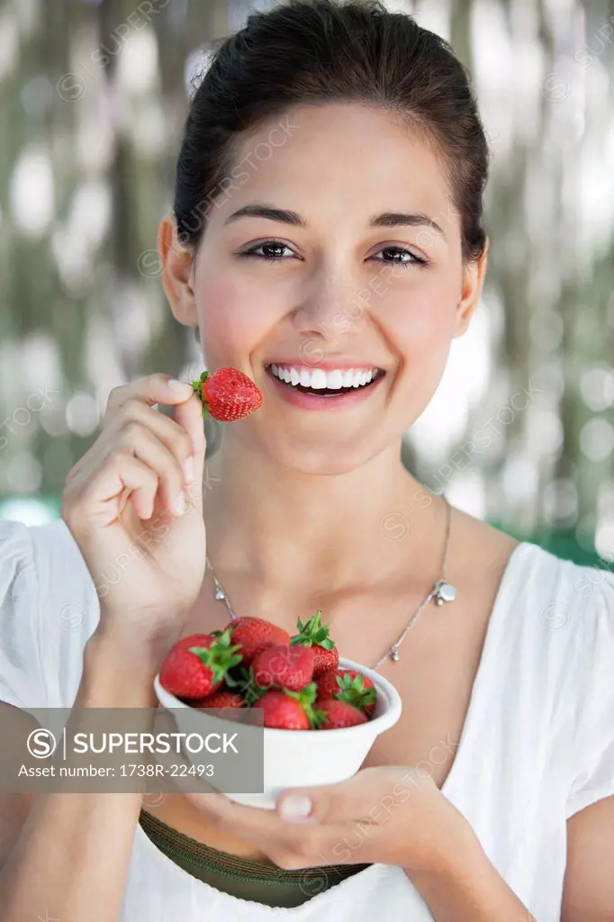 Portrait of a young woman holding a bowl of strawberries
