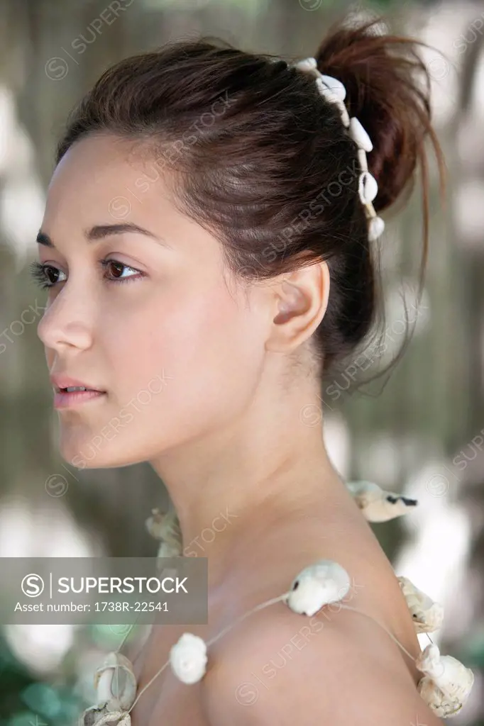 Side profile of a beautiful young woman wearing a shell necklace