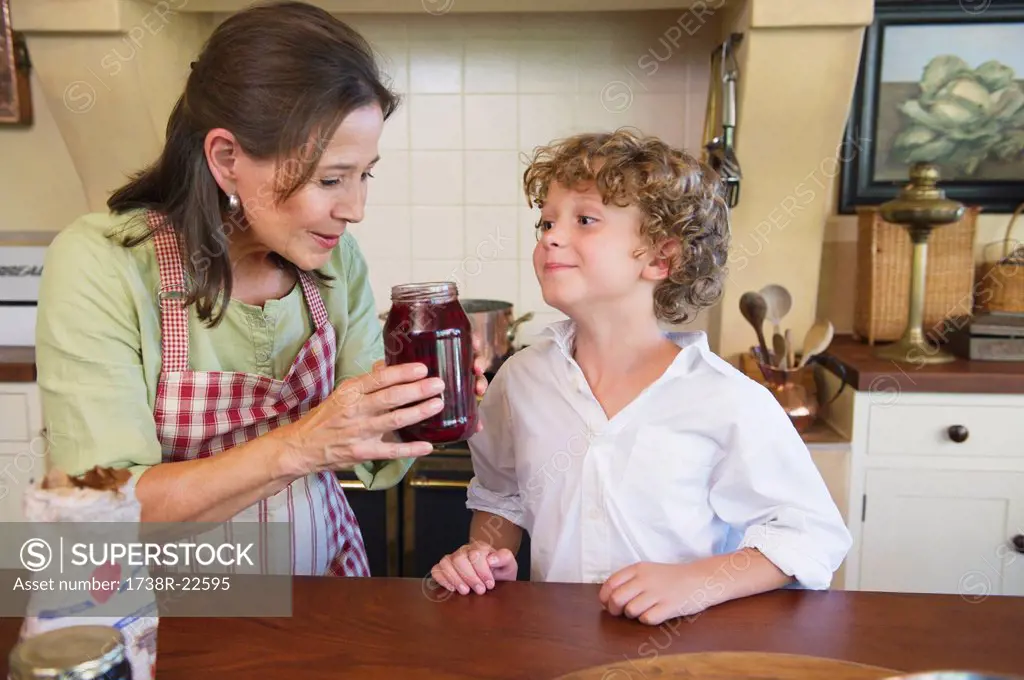 Grandmother and little boy smelling honey at kitchen