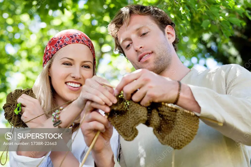 Young couple knitting together and smiling