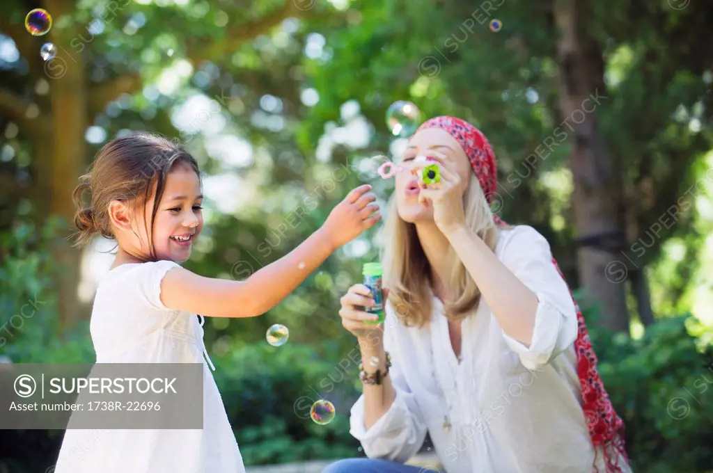 Mother and a little girl playing with bubble wand outdoors