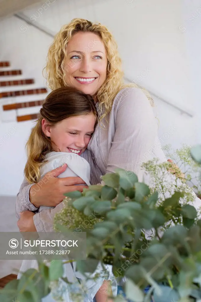 Mid adult woman hugging her daughter and smiling