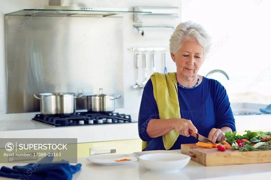 Senior woman cutting vegetable in a kitchen