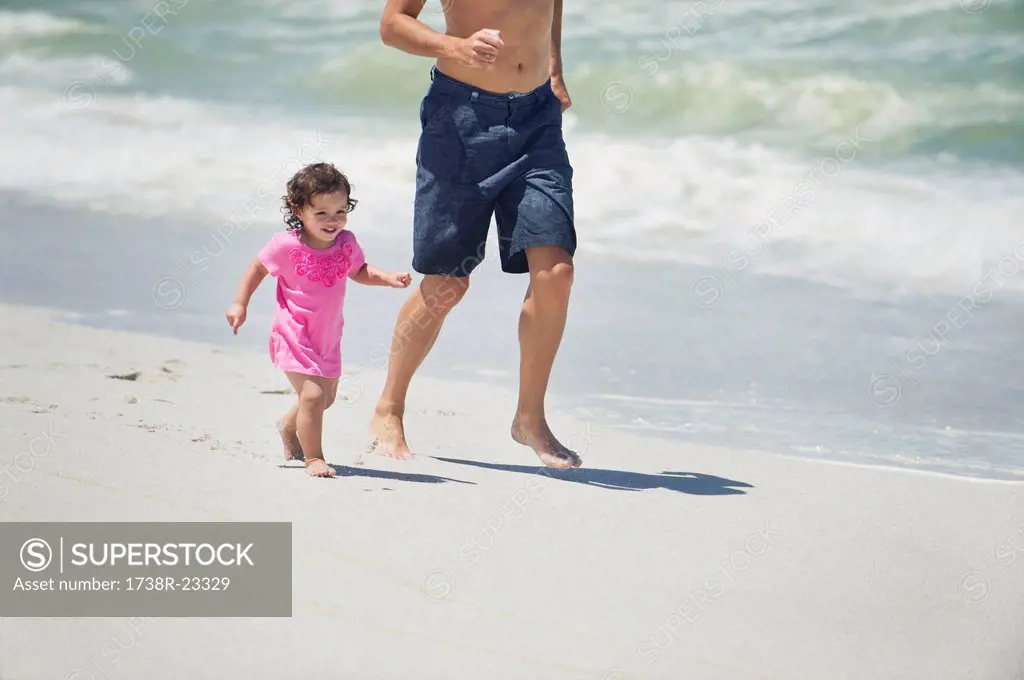 Man running with little daughter on the beach