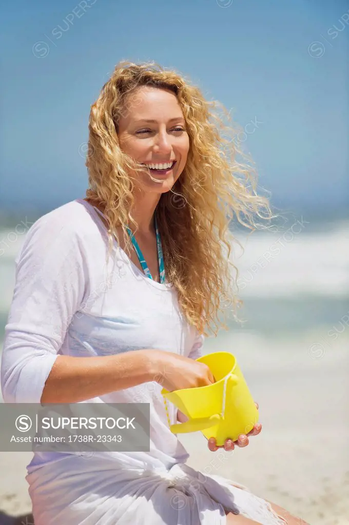 Beautiful woman holding plastic bucket on the beach