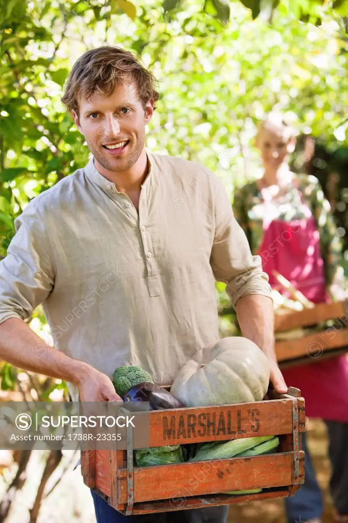 Smiling man holding a crate of vegetables