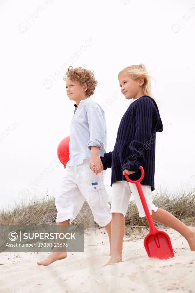 Brother and his sister walking on sand, holding hands