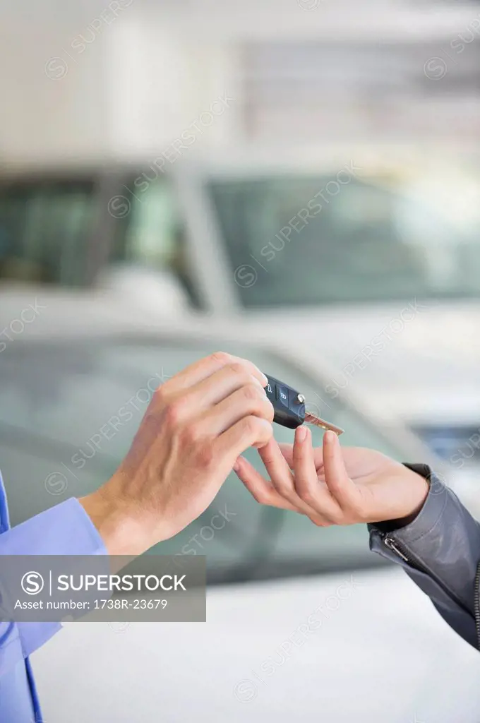Salesman handing car key to woman