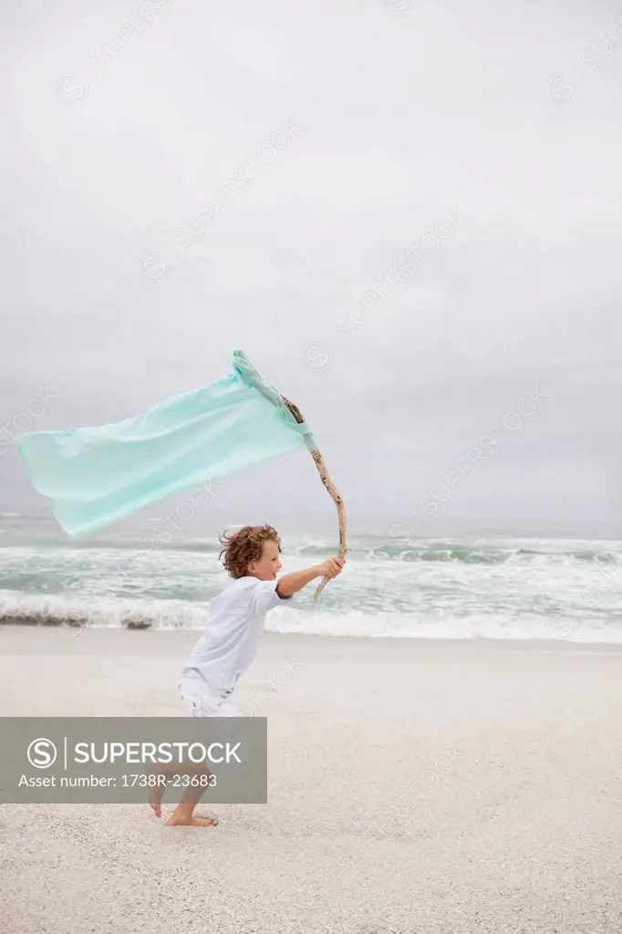 Boy running while holding flag on beach