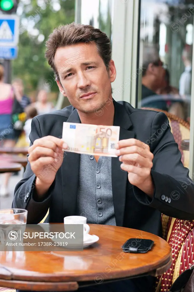 Man showing a 50 Euro banknote in a restaurant, Paris, Ile_de_France, France