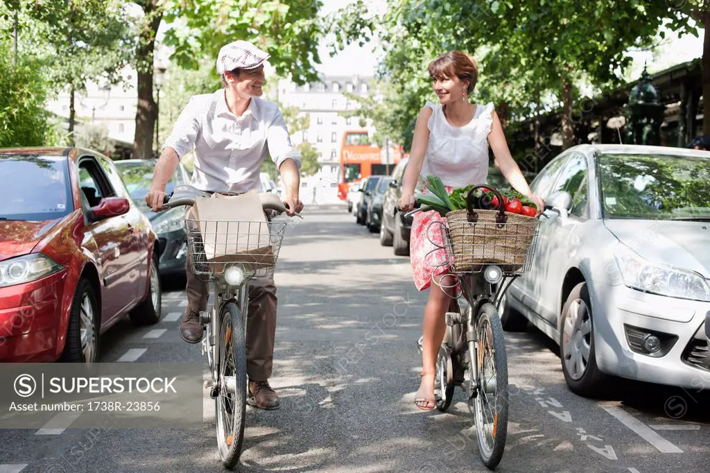 Couple carrying vegetables on bicycles, Paris, Ile_de_France, France