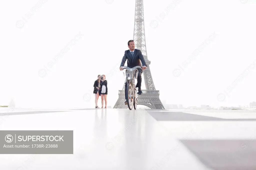 Businessman riding a bicycle with the Eiffel Tower in the background, Paris, Ile_de_France, France