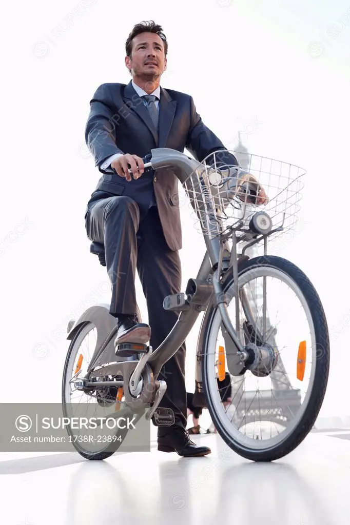 Businessman riding a bicycle with the Eiffel Tower in the background, Paris, Ile_de_France, France