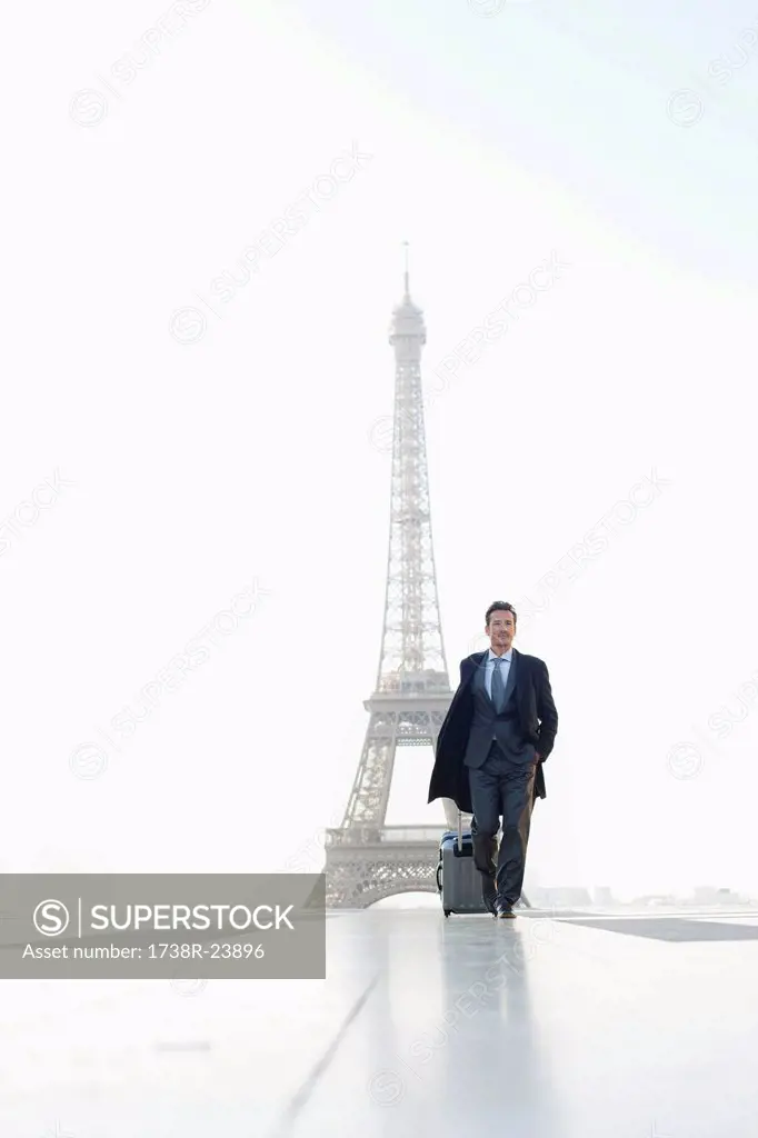 Businessman walking with luggage with the Eiffel Tower in the background, Paris, Ile_de_France, France