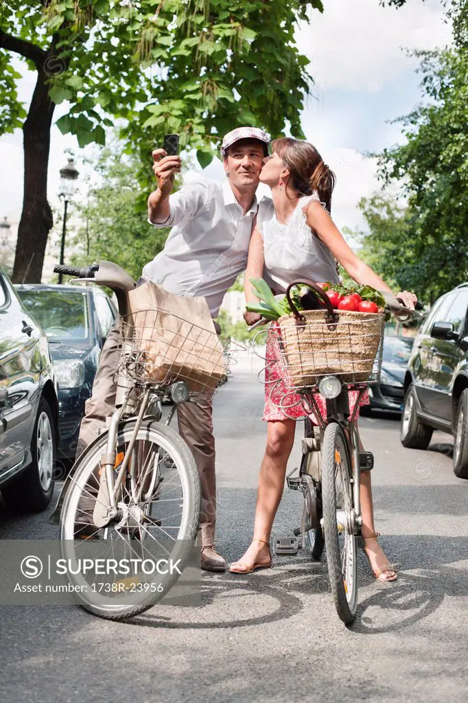 Couple riding bicycles and taking a picture of themselves with a mobile phone, Paris, Ile_de_France, France