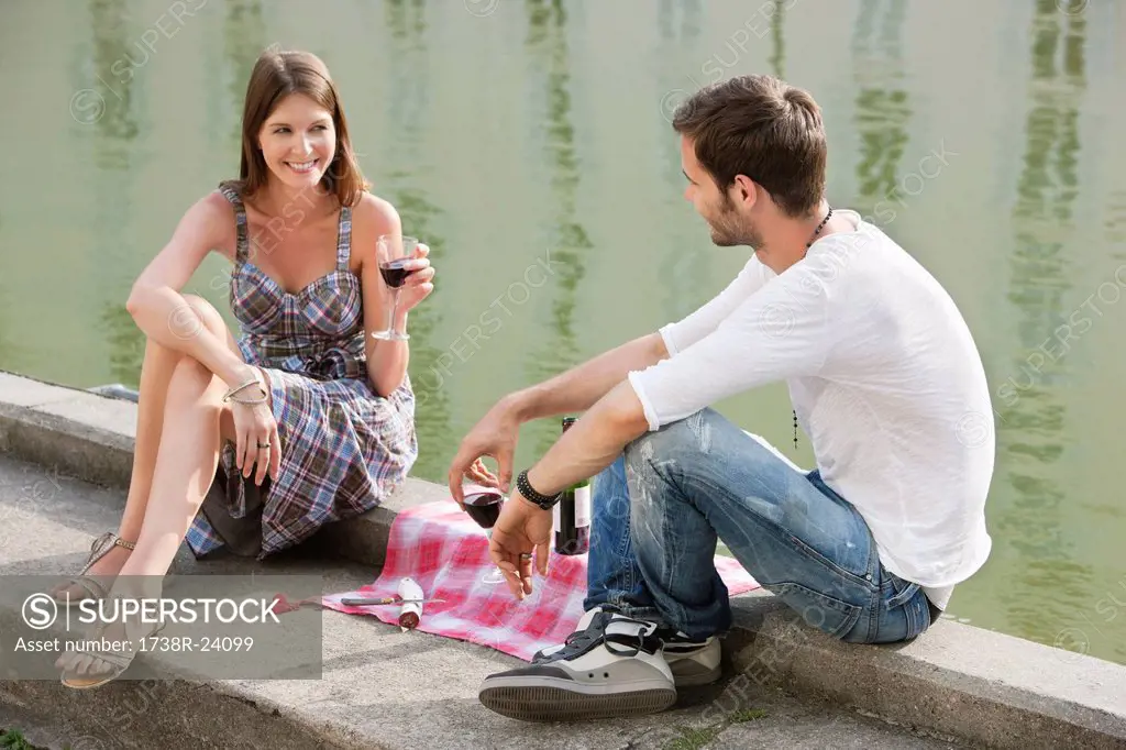 Couple drinking red wine at the ledge of a canal, Paris, Ile_de_France, France