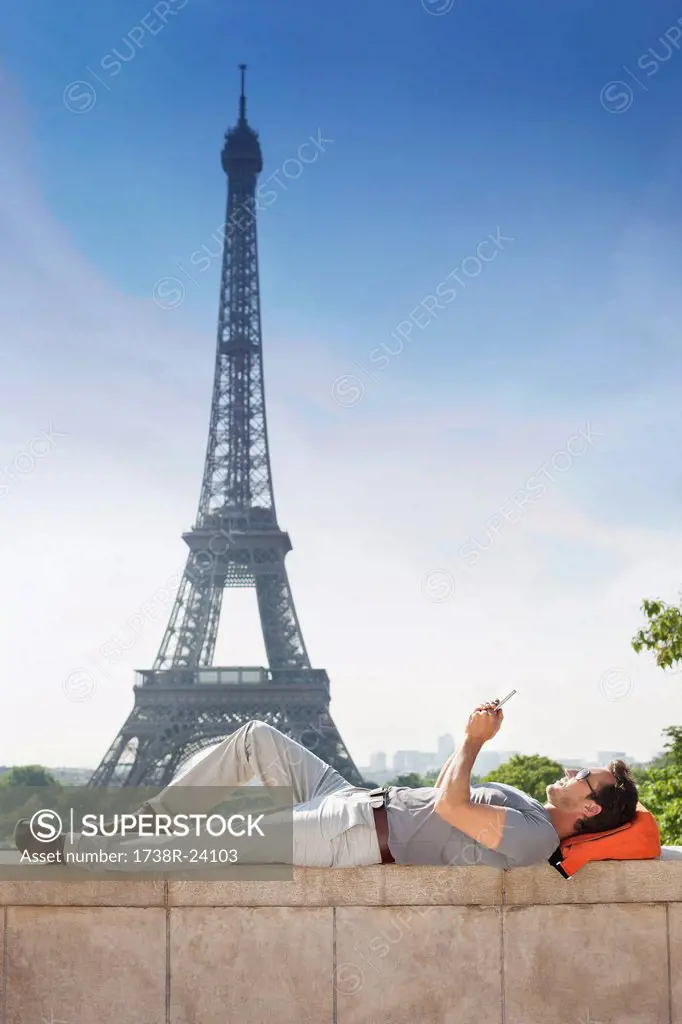 Man lying on a stone wall with the Eiffel Tower in the background, Paris, Ile_de_France, France