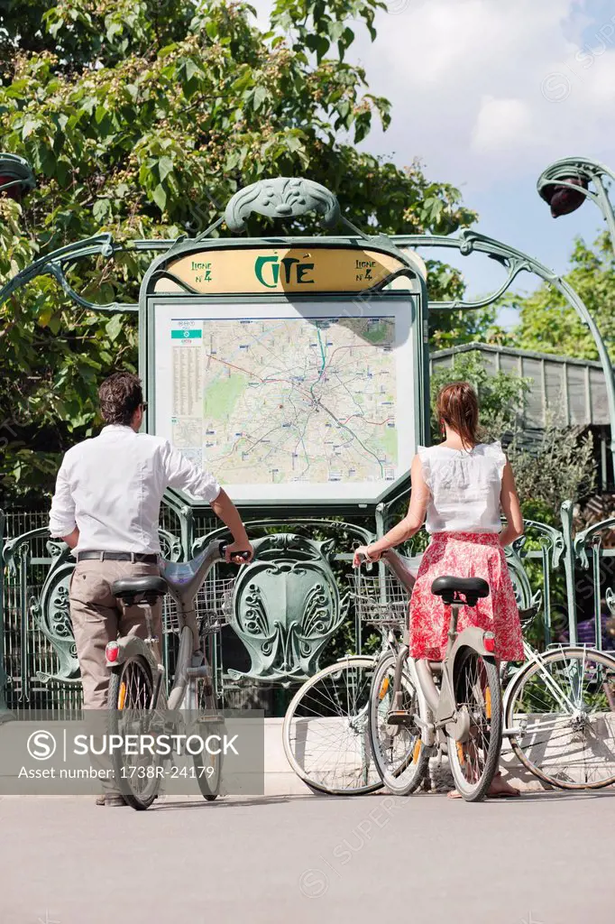 Couple with bicycles looking at a map, Paris, Ile_de_France, France