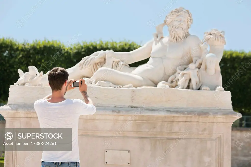 Man taking a picture of a sculpture in a garden, Jardin des Tuileries, Paris, Ile_de_France, France