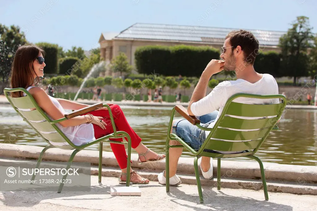 Couple sitting in chairs near a pond in a garden, Bassin octogonal, Jardin des Tuileries, Paris, Ile_de_France, France