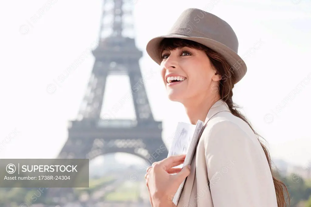 Woman holding a guide book with the Eiffel Tower in the background, Paris, Ile_de_France, France