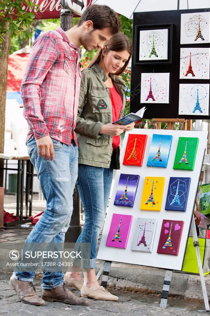 Couple looking at postcards of Eiffel Tower at a market stall, Paris, Ile_de_France, France