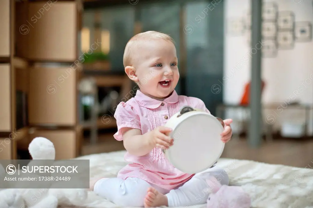 Baby girl playing with a tambourine