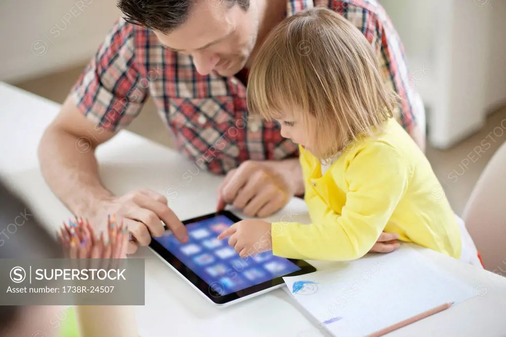 Man teaching digital tablet to his daughter