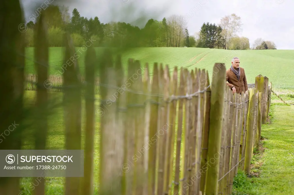 Man standing by fence in a field