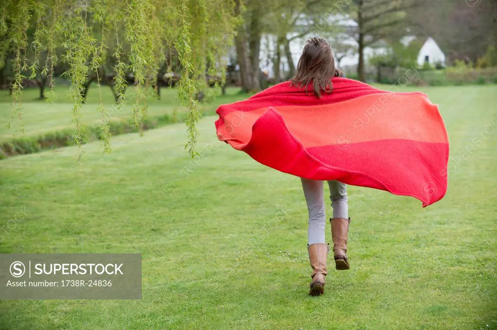 Girl running in a field with a blanket