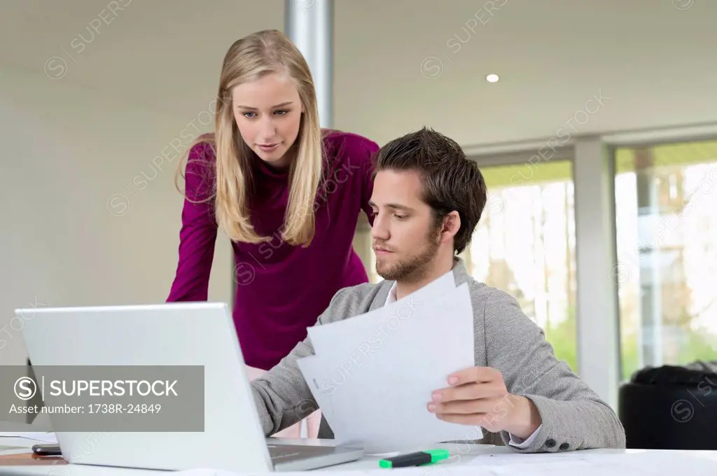 Woman looking at a man working on a laptop