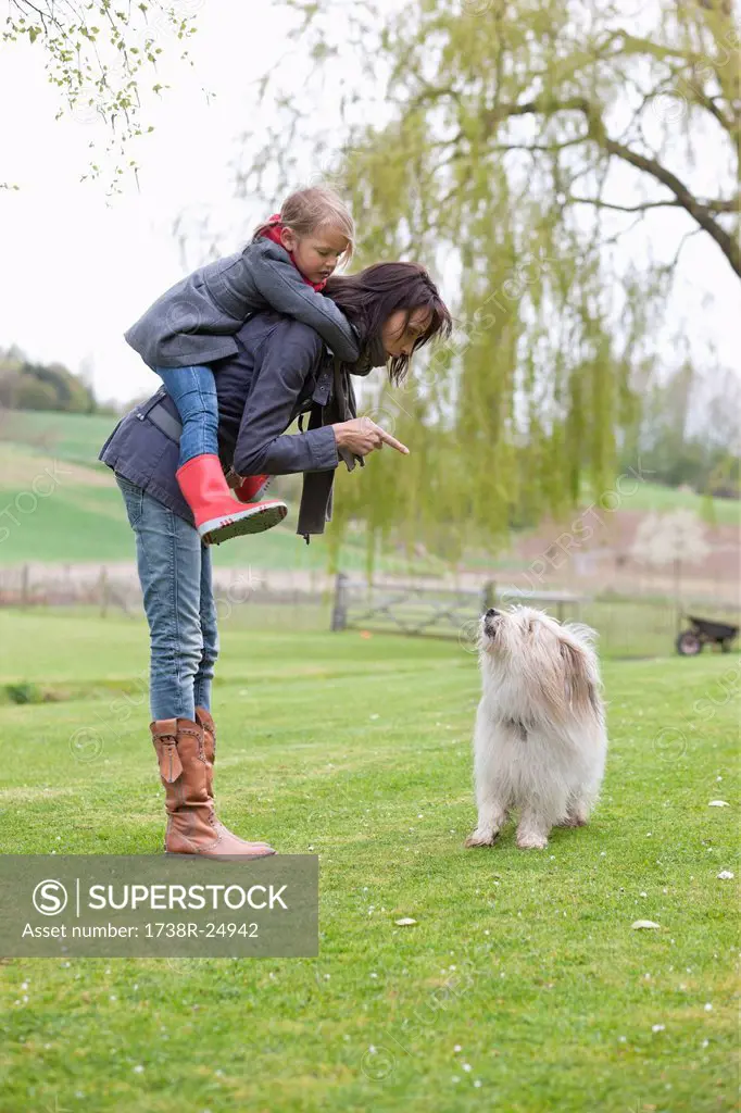Woman carrying her daughter on piggyback and scolding her dog