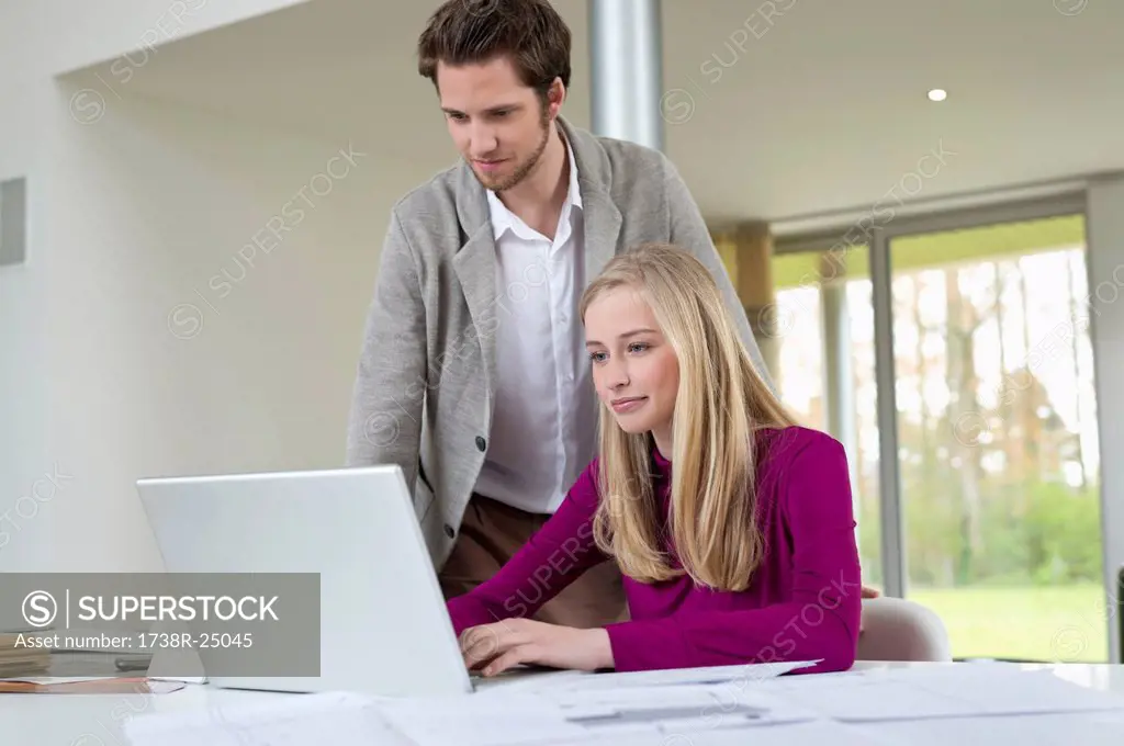 Man looking at a woman working on a laptop