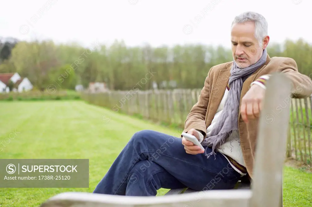 Man text messaging on a mobile phone in a field