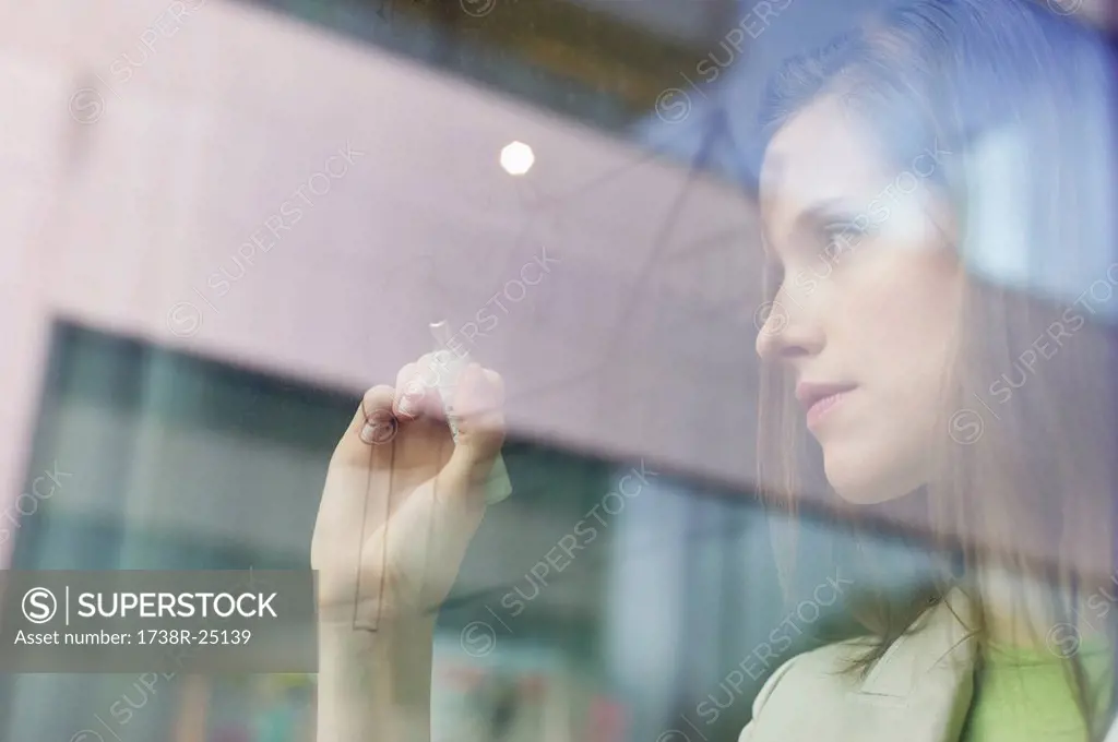 Businesswoman drawing a house on a glass surface