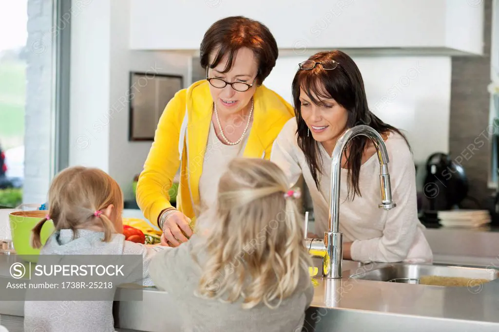 Two girls with her mother and grandmother working in a kitchen