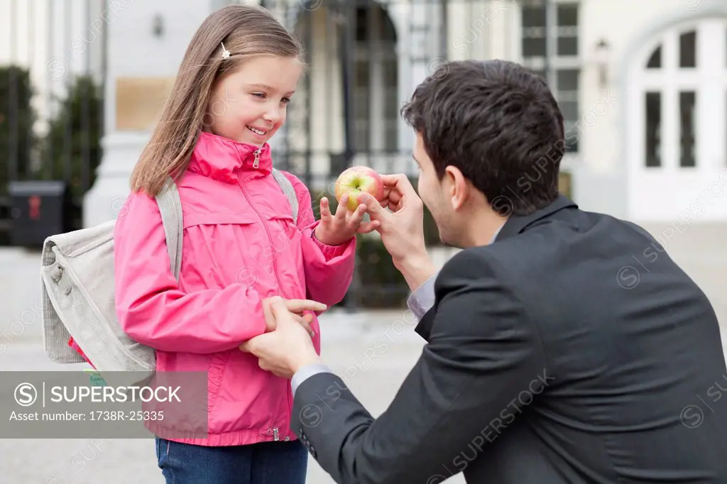 Man giving an apple to his daughter