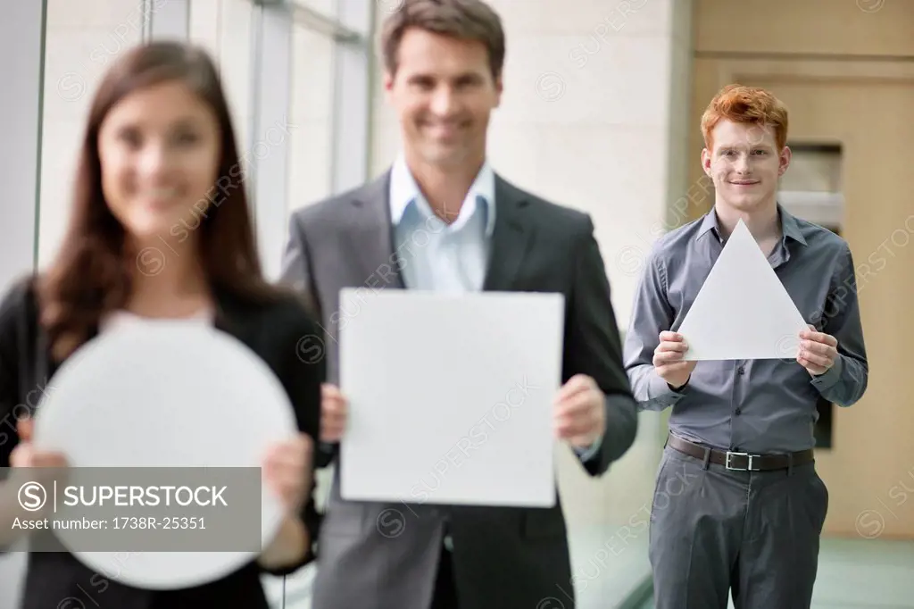 Business executives holding geometrical shaped placards in an office