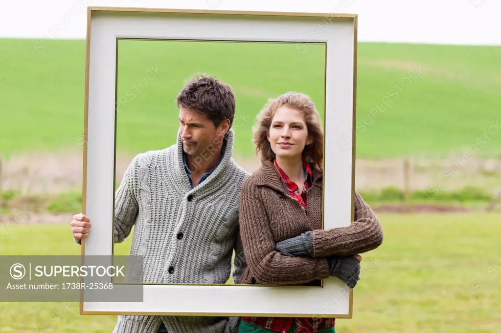 Couple holding a frame in a field