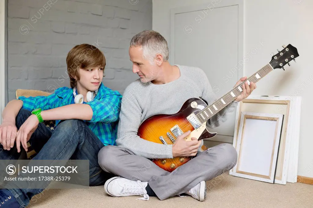 Man playing a guitar with his son at home