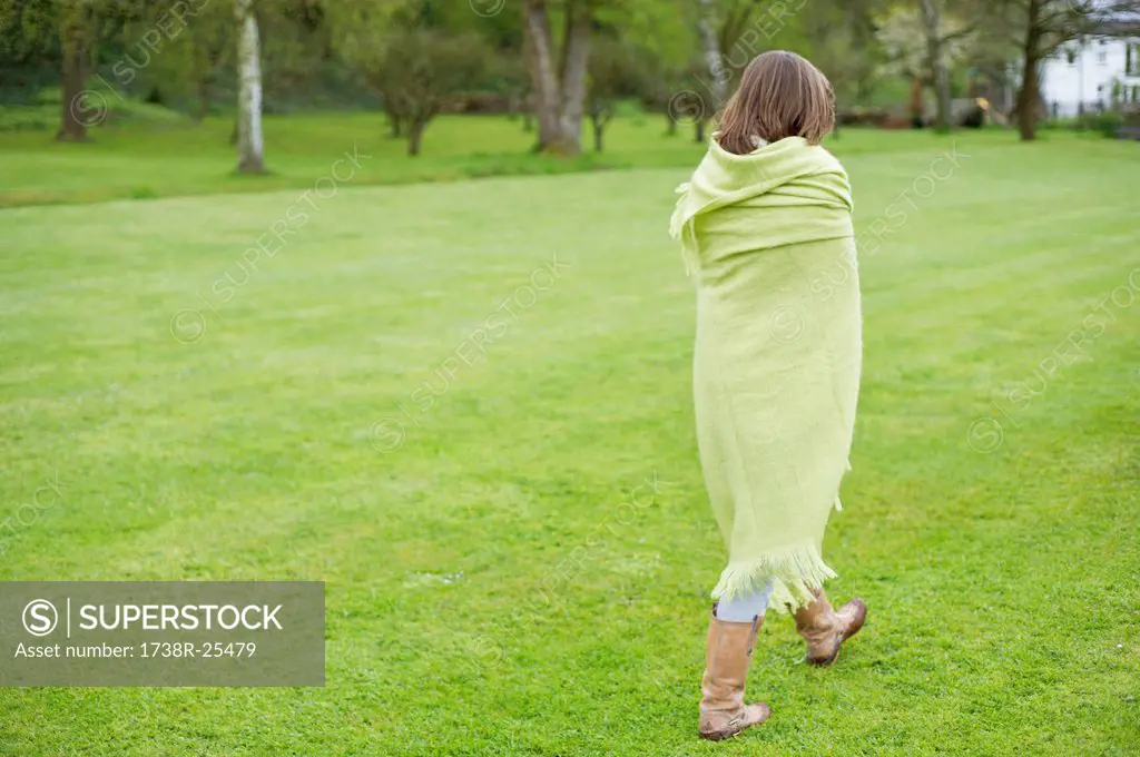 Girl wrapped in a blanket and walking in a field