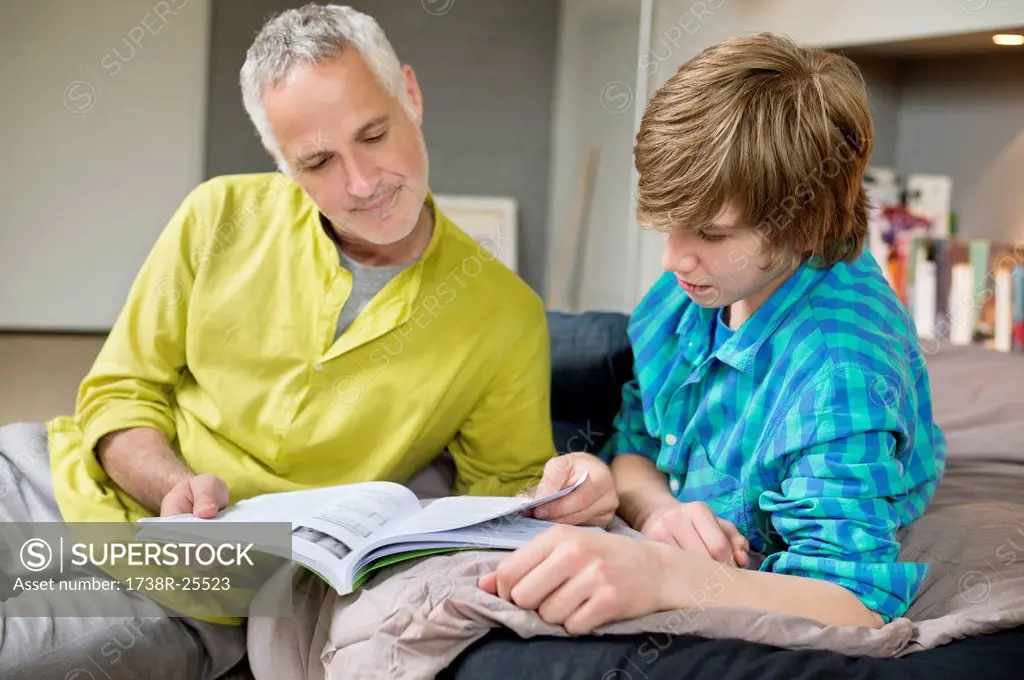 Teenage boy studying with his father at home