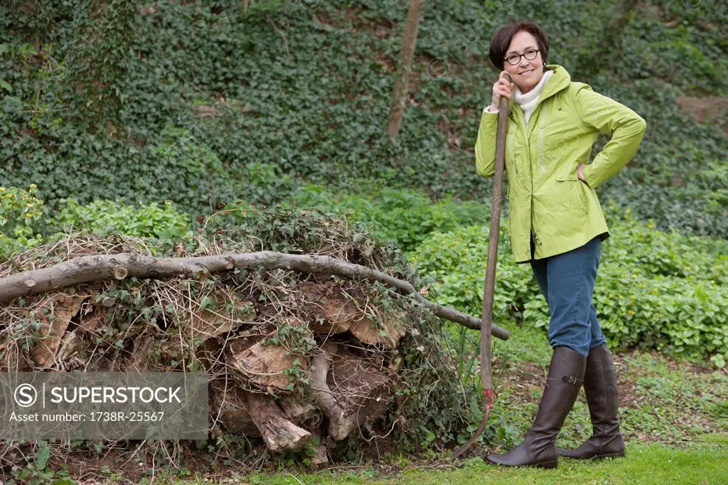 Woman standing with a shovel near a heap of rubbish