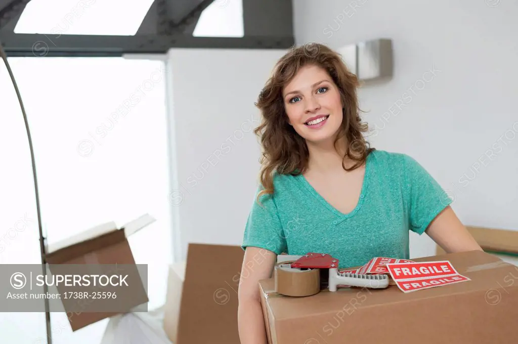 Woman carrying cardboard box and smiling