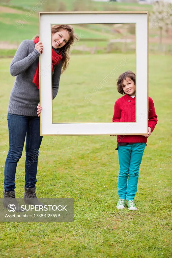 Woman and her son standing with a frame in a park